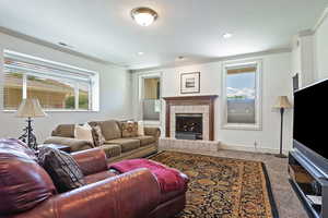 Living room with a tile fireplace, crown molding, and carpet