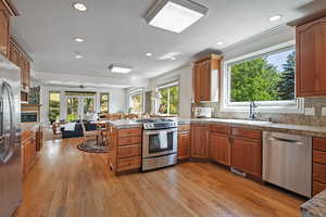 Kitchen featuring appliances with stainless steel finishes, light hardwood / wood-style floors, and decorative backsplash