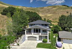 View of front of house with a mountain view, a garage, a front yard, and a balcony