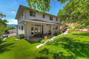 Rear view of property with a patio, a mountain view, a lawn, and french doors