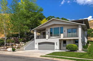 Modern home with a garage, a front yard, and a balcony