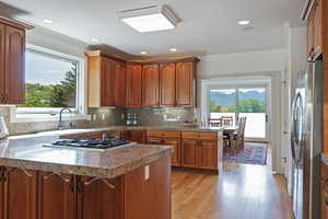 Kitchen with sink, kitchen peninsula, stainless steel appliances, light hardwood / wood-style floors, and decorative backsplash