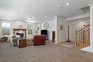 Living room with a fireplace, ornamental molding, and carpet flooring