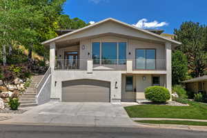 Contemporary home featuring a garage, a balcony, and a front yard