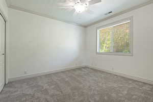 Empty room with light carpet, crown molding, and ceiling fan