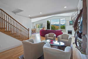 Living room with vaulted ceiling and light hardwood / wood-style flooring