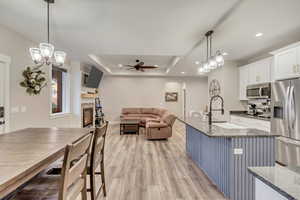 Kitchen with sink, white cabinetry, decorative light fixtures, appliances with stainless steel finishes, and a raised ceiling