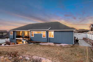 Back house at dusk featuring a yard and a patio area