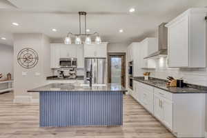 Kitchen with white cabinetry, appliances with stainless steel finishes, a breakfast bar with sink, and granite counter tops