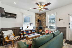 Living room with ceiling fan, wood-type flooring, and a wood stove