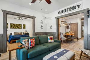 Living room with ceiling fan, stacked washer / drying machine, and light hardwood / wood-style floors