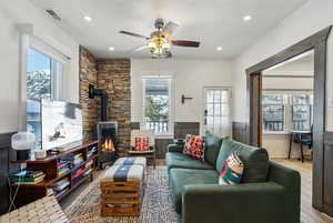 Living room featuring a healthy amount of sunlight, a wood stove, ceiling fan, and light hardwood / wood-style flooring