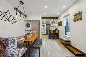 Dining area featuring stacked washer and dryer, light hardwood / wood-style flooring, and a barn door