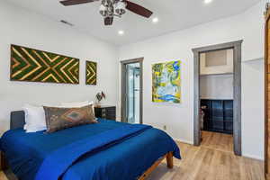 Bedroom with ceiling fan, wood-type flooring, and ensuite bathroom