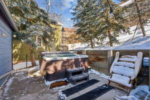 Snow covered patio featuring a hot tub