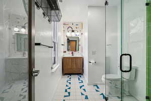 Bathroom with walk in shower, vanity, toilet, and tile patterned flooring