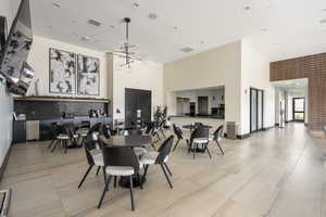 Dining room with a towering ceiling, light tile patterned floors, and a chandelier