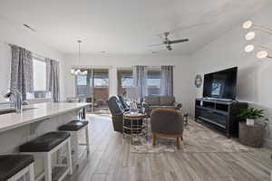 Living room with ceiling fan with notable chandelier, sink, and light hardwood / wood-style floors