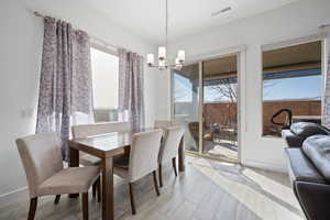 Dining space with a chandelier, light hardwood / wood-style flooring, and a wealth of natural light