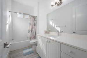 Full bathroom featuring shower / bathtub combination with curtain, vanity, wood-type flooring, and toilet