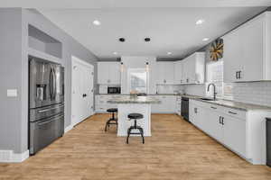 Kitchen featuring white cabinetry, sink, a kitchen island, and black appliances