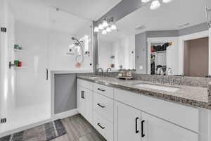 Bathroom featuring vanity and a shower with door