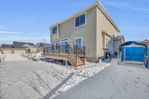 Snow covered house featuring central AC unit and a deck