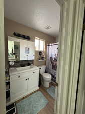 Bathroom with toilet, a textured ceiling, vanity, a shower with shower curtain, and hardwood / wood-style flooring