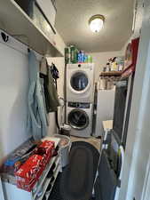 Laundry area with stacked washer and dryer location and a textured ceiling