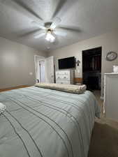 Bedroom featuring carpet, a spacious closet, ceiling fan, a textured ceiling, and a closet