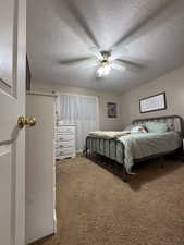 Carpeted bedroom with ceiling fan and a textured ceiling