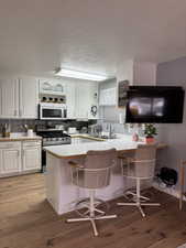 Kitchen featuring stainless steel range with gas stovetop, kitchen peninsula, and white cabinets