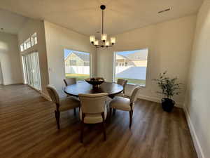 Dining area with dark wood-type flooring and a notable chandelier