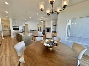 Dining room featuring sink, ceiling fan with notable chandelier, a textured ceiling, and light hardwood / wood-style flooring