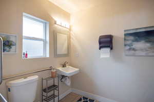 Bathroom featuring sink, toilet, and tile patterned flooring