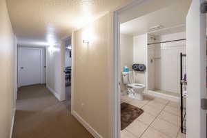 Corridor with a textured ceiling and light tile patterned floors