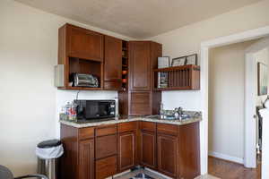 Kitchen with sink, backsplash, light hardwood / wood-style floors, and a textured ceiling