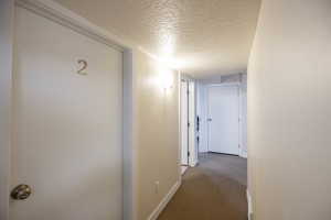 Corridor with a textured ceiling and carpet