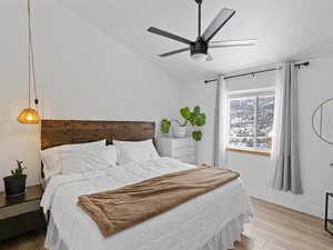 Primary bedroom featuring hardwood / wood-style flooring, lofted ceiling, and ceiling fan