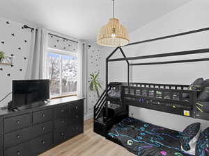 Bedroom featuring hardwood / wood-style flooring and lofted ceiling.