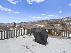 Large deck with a playground, a mountain view, and area for grilling