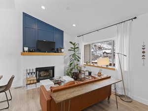 Living room with light hardwood / wood-style flooring and vaulted ceiling, gorgeous fireplace and decorative accent wall.