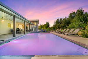 Pool at dusk featuring a patio area