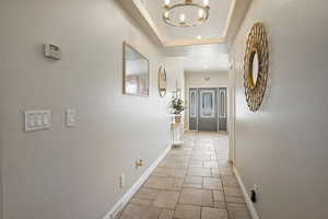 Corridor with a raised ceiling and a chandelier