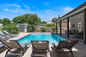 View of pool featuring a patio and a storage unit