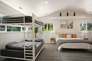 Carpeted bedroom with multiple windows, lofted ceiling, and a textured ceiling