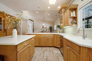 Kitchen featuring lofted ceiling, sink, dishwasher, hanging light fixtures, and kitchen peninsula