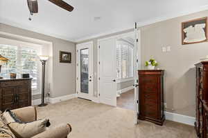 Entryway featuring a wealth of natural light, ornamental molding, light colored carpet, and ceiling fan