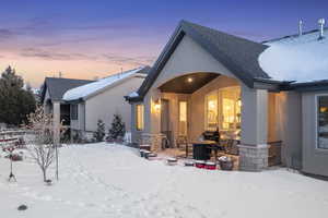 Snow covered back of property with an outdoor fire pit