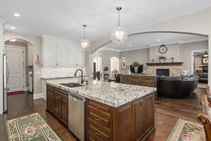 Kitchen with sink, a center island with sink, dark hardwood / wood-style floors, pendant lighting, and stainless steel appliances